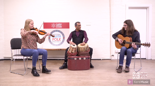 video still showing three tutors playing instruments in a white room with wooden floorboards